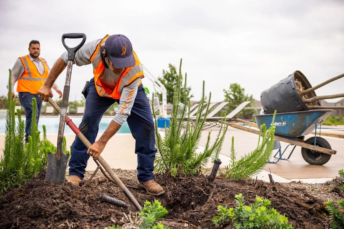 Crew performing common-area fuel reduction in an HOA greenbelt with townhomes in the background
