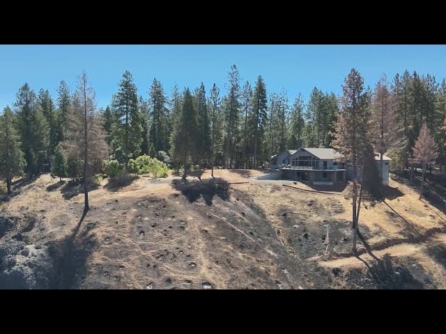 Featured photo: a mountain home with completed defensible space — cleared first five feet, spaced trees, and healthy forest beyond